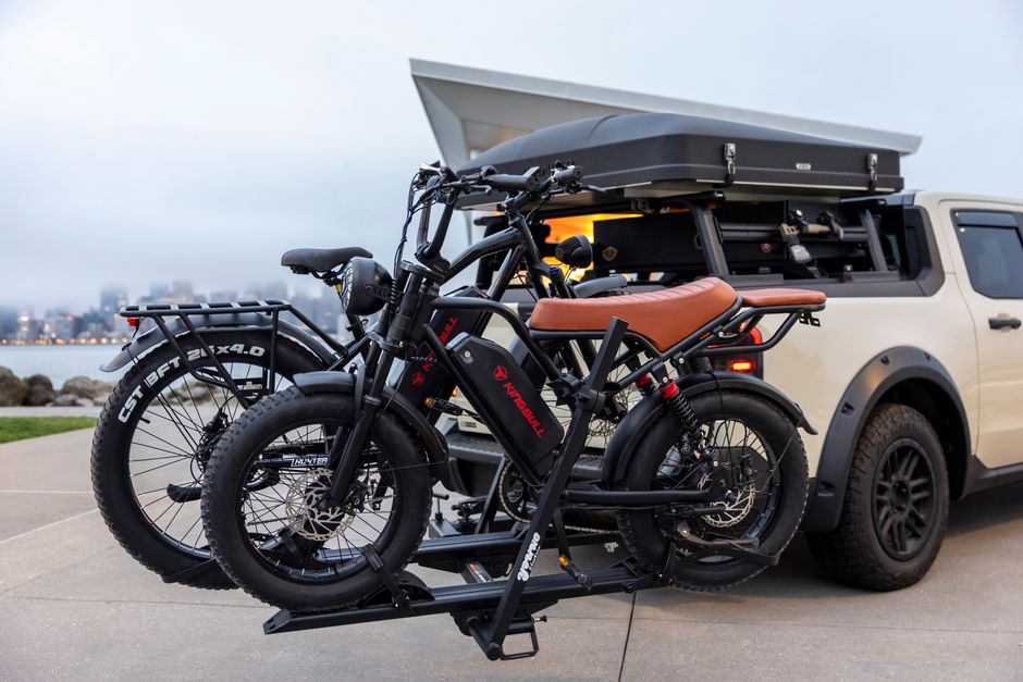 Electric bikes on car rack by a waterfront, illustrating outdoor adventures and modern travel.